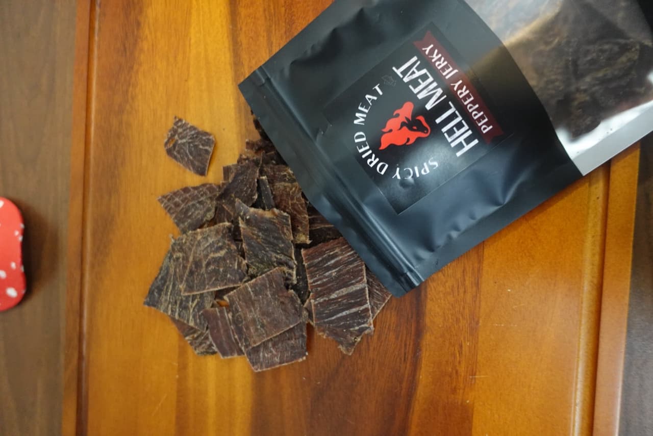 ซอง Peppery Jerky เปิดพร้อมเนื้อเทลงบนเขียงไม้